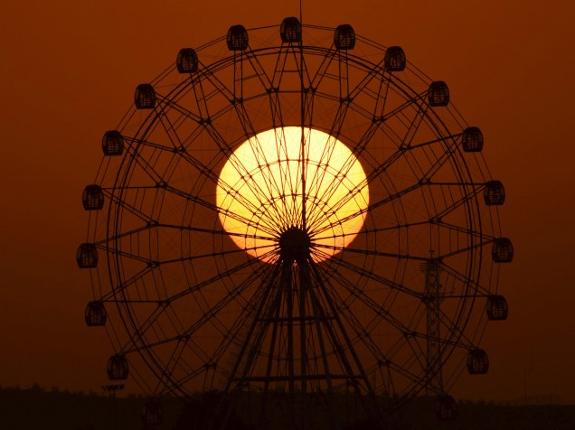Pôr do sol é registrado por trás de uma roda gigante na cidade de Korla, na China - 10/11/2015