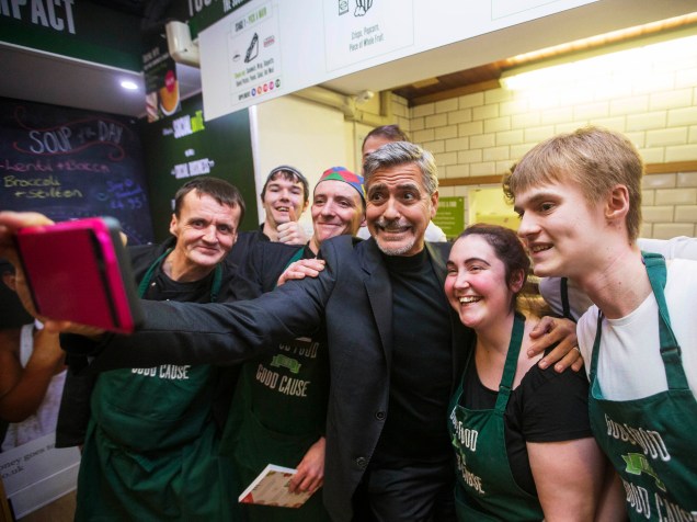 O ator George Clooney posa para foto com ex-moradores de rua que hoje são funcionários de uma cafeteria beneficente em Edimburgo, na Escócia - 12/11/2015