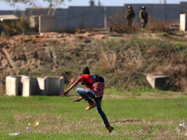 Manifestante palestino usa uma funda para jogar pedras em tropas israelenses, na Cisjôrdania - 12/11/2015