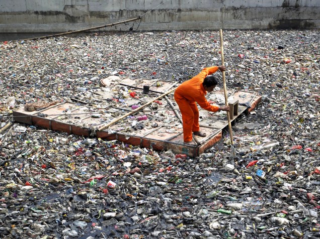 Um funcionário do governo limpa detritos flutuantes em um rio no norte de Jacarta, na Indonésia - 13/11/2015