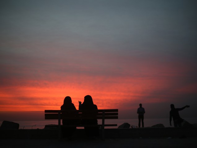 Mulheres palestinas sentam-se em banco de uma praia, durante o pôr do sol na cidade de Gaza - 25/11/2015<br><br>