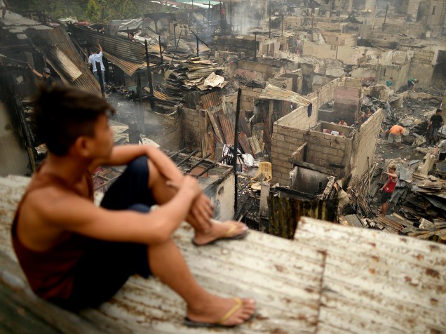 Garoto filipino olha para casas destruídas após incêndio em uma favela no subúrbio de Manila (Filipinas). O incêndio de grandes proporções destruiu mais de 800 casas, deixando milhares de famílias desabrigadas - 26/11/2015