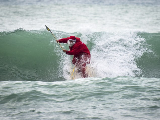 O surfista Federico Piccinaglia pega onda vestido de Papai Noel, em Levanto, na Itália - 04/12/2015