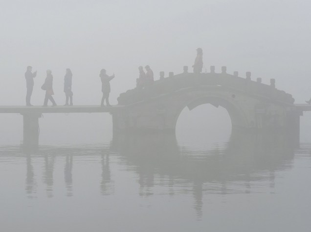 Em Hangzhou, na China, turistas andaram por uma ponte sobre o Lago Oeste em meio a uma densa neblina e poluição atmosférica