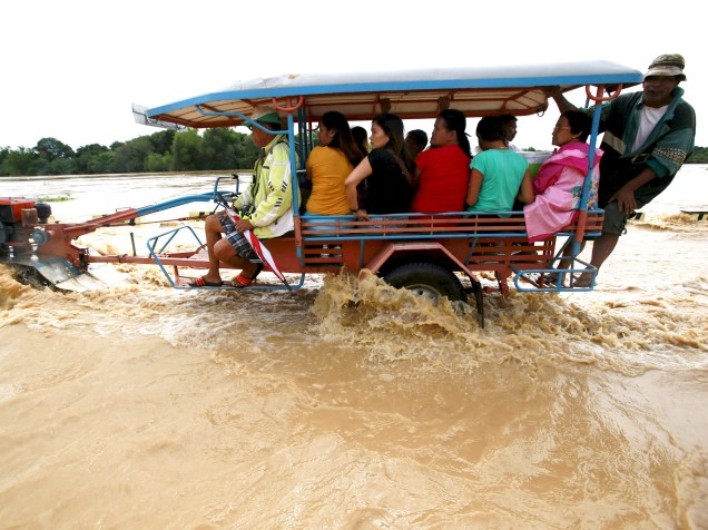 Ao norte de Manila, nas Filipinas, passageiros viajam em trator adaptado para cruzar estrada inundada após a passagem do tufão Melor pelo país. De acordo com a imprensa local, mais de 60 mil famílias ficaram desabrigadas - 17/12/2015
