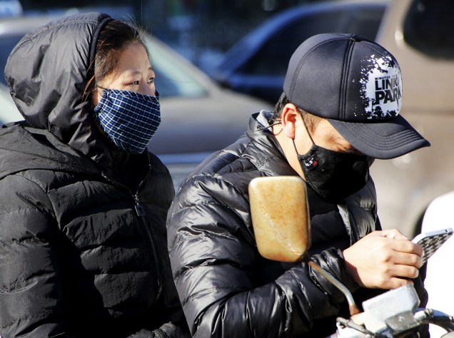 Casal usa máscara de proteção para evitar a poluição nas ruas de Pequim, China, nesta sexta-feira (18)