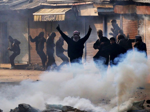 Manifestantes muçulmanos enfrentam uma cortina de gás lacrimogêneo em Srinagar, na Caxemira, no norte da Índia, nesta sexta-feira (18). Protesto, realizado depois de preces, é contra o domínio indiano sobre a Caxemira, região também disputada pelo Paquistão