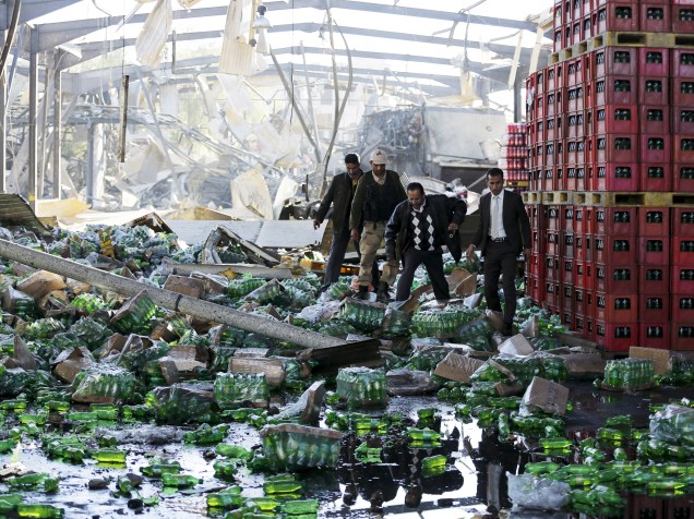 Funcionários observam o local onde uma fábrica de bebidas da Coca-Cola foi atingida por ataques aéreos em Sanaa, capital do Iêmen - 30/12/2015