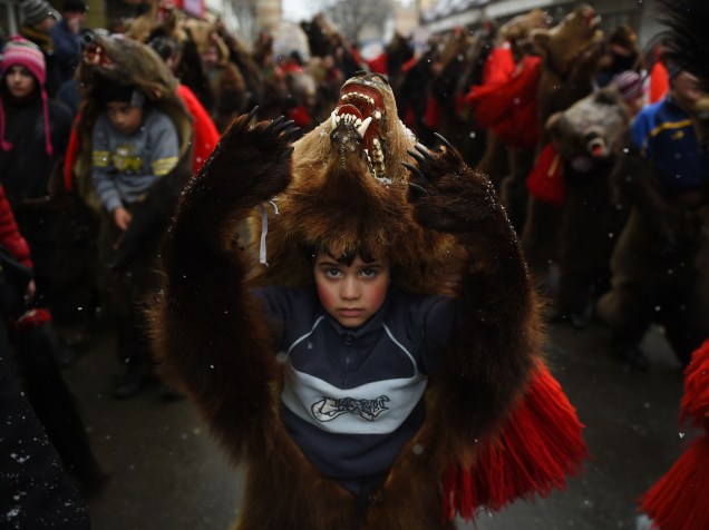 Criança usa a pele de um urso durante uma parada para afastar os maus espíritos do ano que passou, na cidade de Comanesti, na Romênia - 30/12/2015
