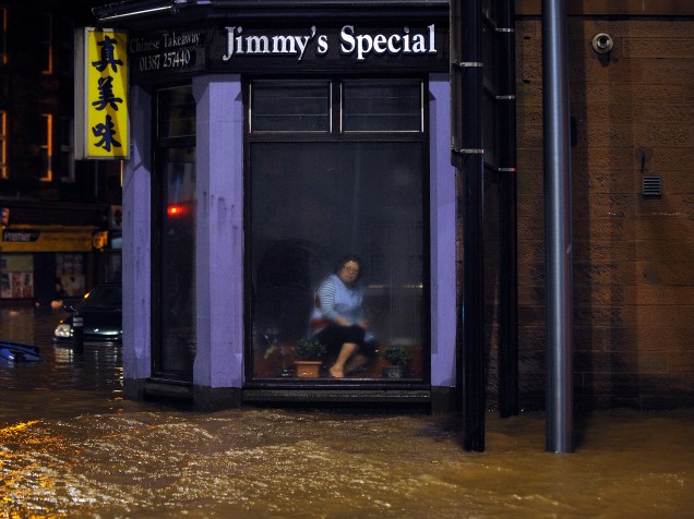 Mulher sentada em um restaurante chinês observa a inundação pela janela, em Dumfries, Escócia - 30/12/2015