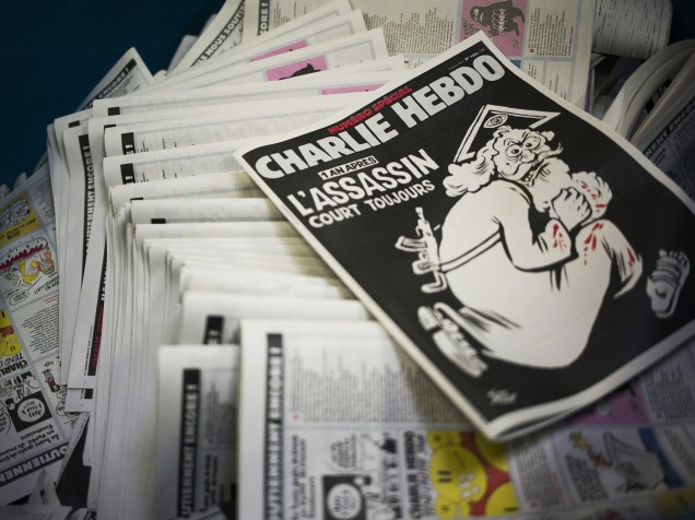 O semanário satírico Charlie Hebdo chega às bancas com uma capa especial para marcar um ano dos atentados à redação da publicação em Paris. A frase "o assassino ainda está em fuga" acompanha uma imagem de Deus correndo com um fuzil nas costas e as mãos sujas de sangue -  04/01/2016