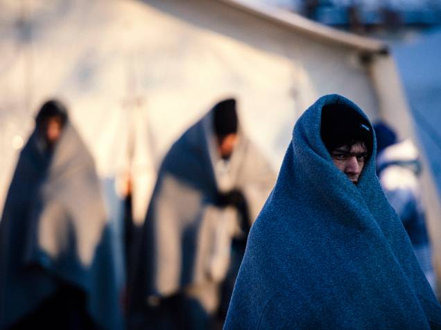 Refugiados se aquecem com cobertores enquanto aguardam um ônibus em um acampamento de registros na cidade sérvia de Presevo - 20/01/2016