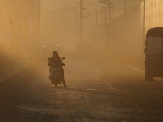 Motociclista atravessa uma nuvem de poeira, perto das obras de construção de novos complexos residenciais em Kunming, na província chinesa de Yunnan - 20/01/2016