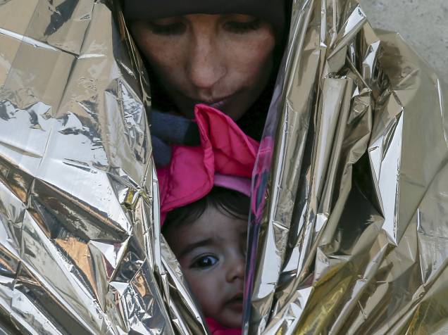 Refugiada protege sua filha em um cobertor térmico, enquanto espera por um trem para a Croácia, em uma estação em Presevo, na Sérvia - 20/01/2016