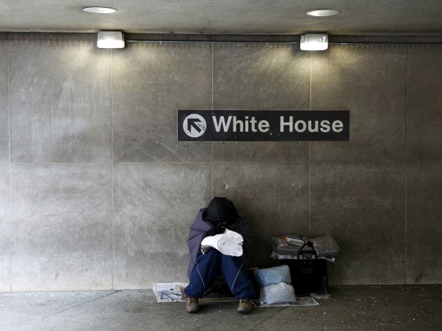 Morador de rua tenta se aquecer enquanto fica entrada da estação de metrô nos arredores da Casa Branca, em Washington (EUA)