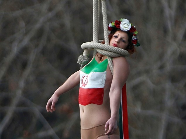 Uma ativista de topless do grupo de direitos das mulheres Femen, se pendura em uma ponte para protesto contra o presidente do Irã, Hassan Rohani, durante sua visita em Paris, França<br><br>