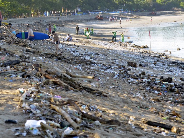 Turistas caminham em meio à grande quantidade de lixo que se acumulou nas areias da praia de Kuta, em Bali, na Indonésia. A sujeira foi trazida por ventos sazonais
