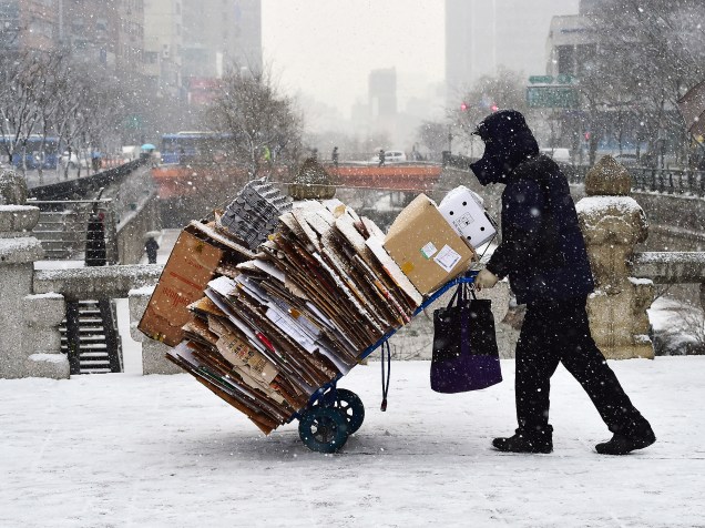Um homem empurra um carrinho contendo papéis  durante uma nevasca em Seul, capital da Coreia do Sul