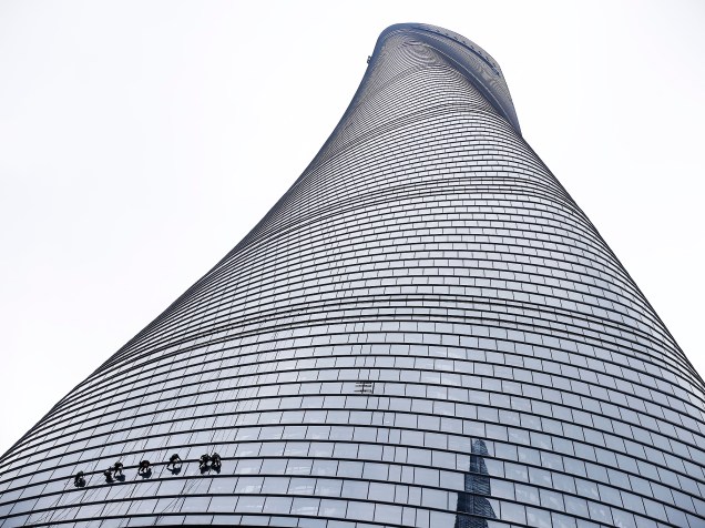 Funcionários são fotografados no exterior do arranha-céu, "Shanghai Tower", no distrito financeiro de Pudong, em Xangai, na China