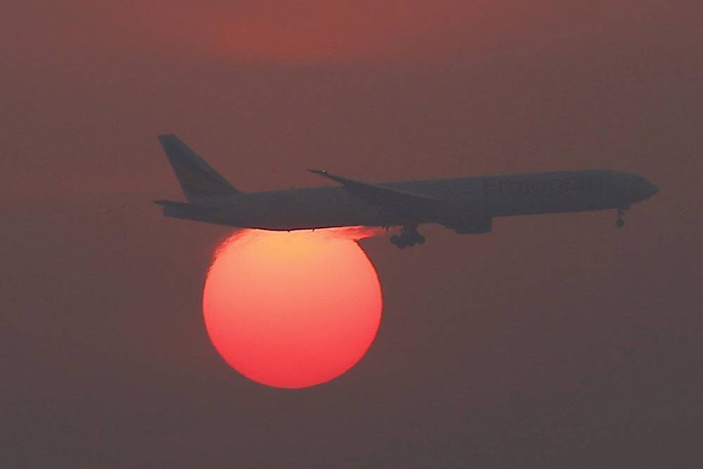 Avião é visto em frente ao sol poente sobre o Aeroporto Internacional de Pequim, na China