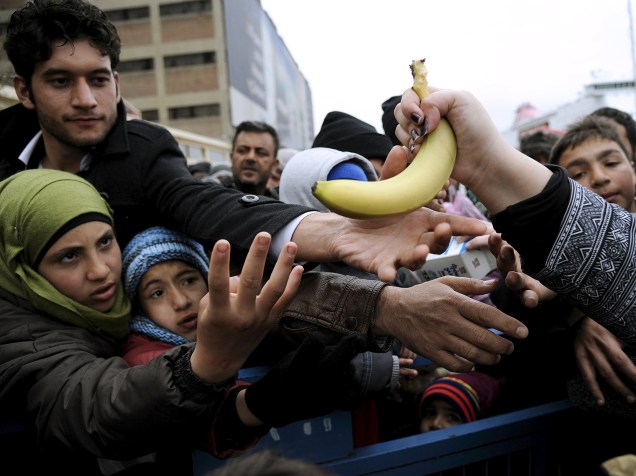  Imigrantes chegam para receber comida entregues por voluntários em acampamento de refugiados em Piraeus, Grécia<br>