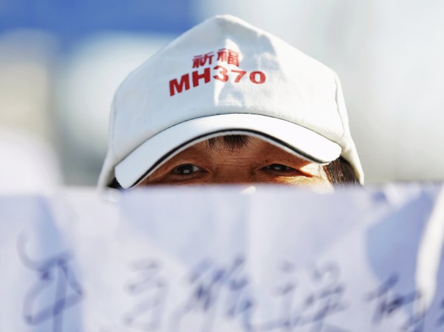 Familiar de passageiro do voo MH370 da Malaysia Airlines segura cartaz durante cerimônia em templo em Pequim, China. Nesta terça-feira faz dois anos que o avião com 239 passageiros desapareceu pouco depois de decolar do aeroporto de Kuala Lumpur