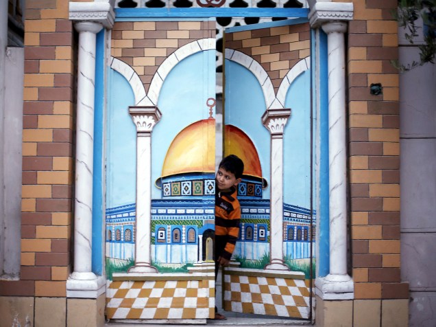 Menino olha da porta de sua casa uma manifestação de militantes do Hamas para marcar o décimo segundo aniversário da morte do xeque Ahmed Yassin, antigo líder do grupo fundamentalista palestino, na Cidade de Gaza - 23/03/2016