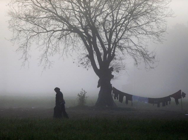 Uma mulher refugiada é vista ao amanhecer em acampamento improvisado na fronteira da Grécia com a Macedônia, perto da aldeia de Idomeni