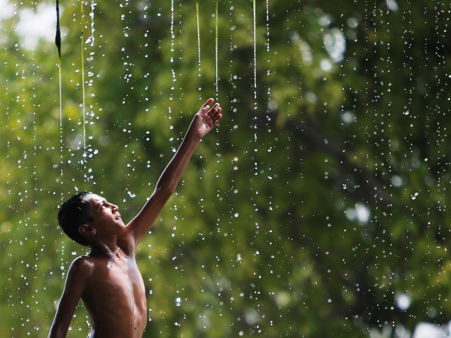Menino se refresca em uma fonte durante um dia quente em Nova Délhi, na Índia - 12/05/2016
