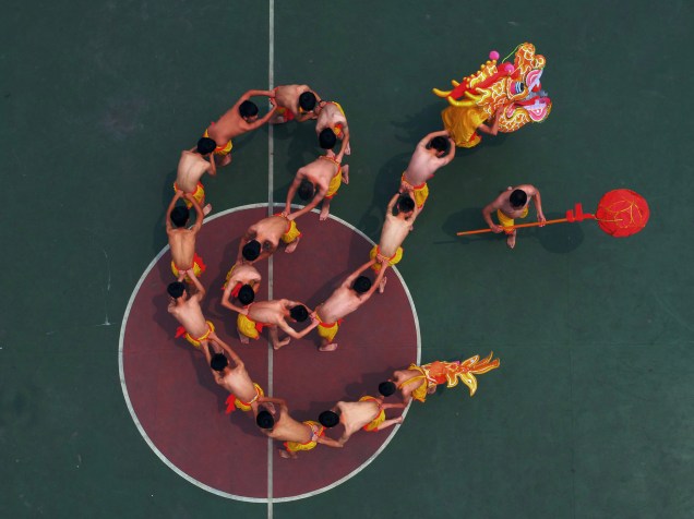 Alunos aprendem a executar uma dança do dragão sob a instrução de um artista local em um parque da cidade de Chongqing, na China
