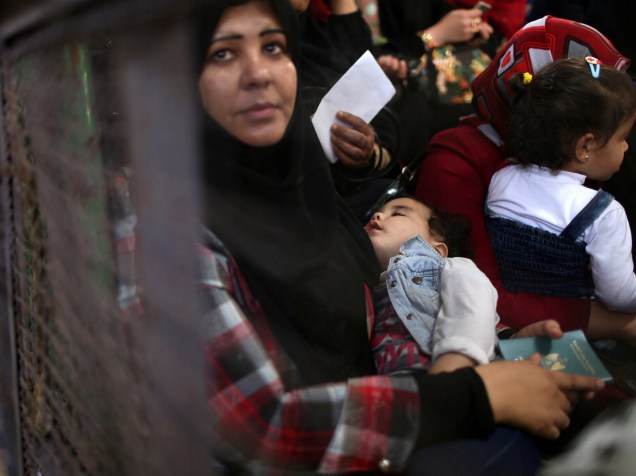 Mulher segura sua filha enquanto aguarda por uma autorização de viagem para atravessar para o Egito através do posto fronteiriço de Rafah na Faixa de Gaza - 12/05/2016