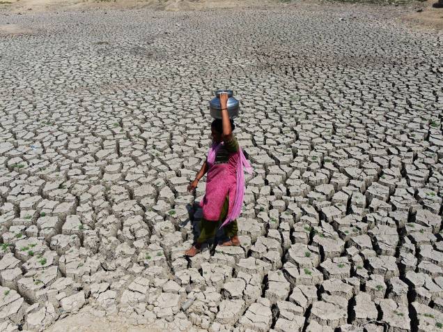 Mulher caminha pelo leito ressecado do rio indiano Chandola, com uma lata equilibrada na cabeça a fim de reabastecer seu reservatório. A Índia enfrenta uma das mais severas crises de água que já afetou o país - 20/05/2016