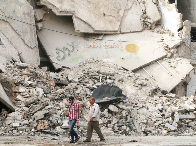 Homens andam próximos à prédio destruído, no distrito de al-Fardous, em Aleppo, norte da Síria - 26/05/2016