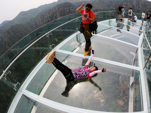Menina deita em uma plataforma de vidro, enquanto posa para foto, em Pequim, na China - 27/05/2016