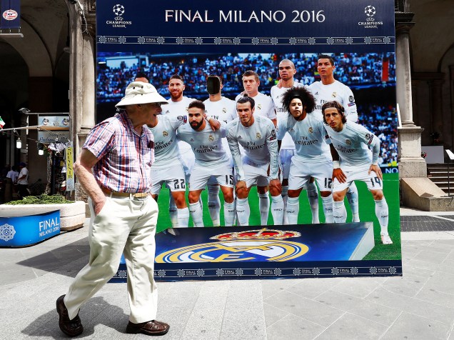Homem caminha ao lado de pôster anunciando a final da Liga dos Campeões da Europa, na Praça Duomo, em Milão, na Itãlia. A grande final do torneio será disputada entre Real Madrid e Atlético de Madrid - 26/05/2016