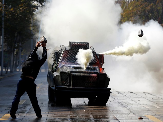 Estudante joga pedra contra veículo da polícia, durante manifestação para exigir mudanças no sistema de ensino, em Santiago, no Chile - 21/04/2016