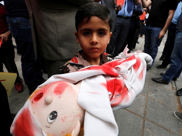 Garoto segura boneco "ensaguentado", em protesto contra o apoio da Rússia ao regime sírio. O protesto acontece em frente à embaixada russa, em Amã - 03/05/2016
