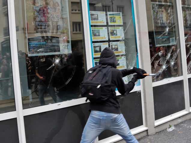 Manifestante mascarado quebra a vidraça de uma agência bancária em Rennes, oeste da França, durante protesto contra as reformas da lei trabalhista proposta pelo governo - 23/06/2016