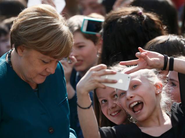 Crianças fazem selfies enquanto a chanceler alemã, Angela Merkel assina autógrafos durante visita a uma escola secundária francesa em Berlim - 03/05/2016