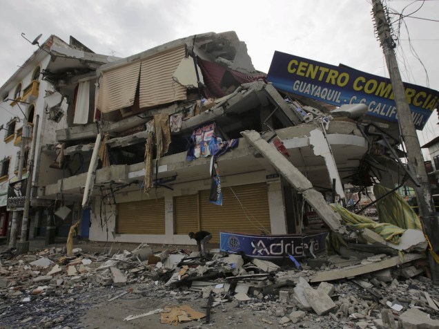 Homem recolhe objetos, próximo a uma loja que desmoronou, após os fortes terremotos que atingiram o Equador - 21/04/2016