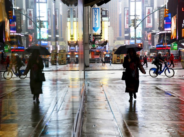 Mulher caminha com um guarda-chuva, durante chuva na Times Square, em Nova York, nesta quarta (24)