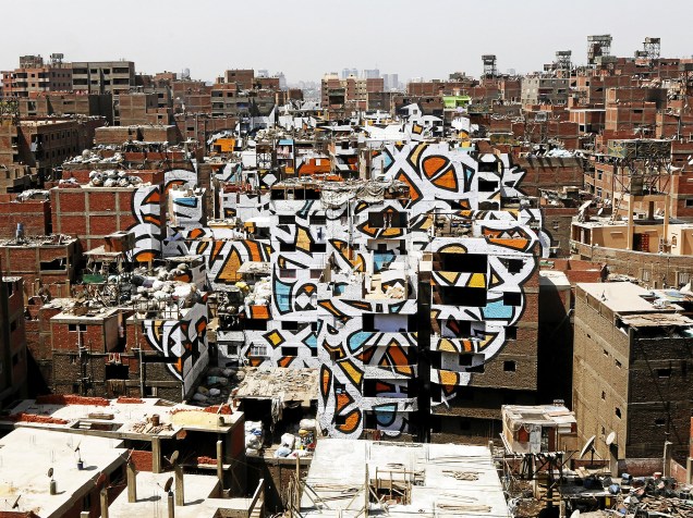 Artista franco-tunisino El Seed pinta mural nas paredes prédios e casas de uma favela de Zaraeeb, região conhecida como "Cidade do Lixo", no leste do Cairo, Egito