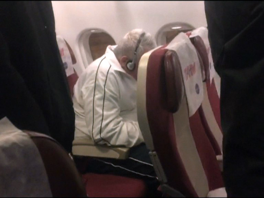 Pizzolato tenta esconder o rosto em avião