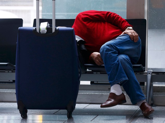 Um passageiro dorme no aeroporto de Frankfurt, na Alemanha, após a companhia aérea Lufthansa cancelar centenas de voos depois que funcionários entrarem em greve