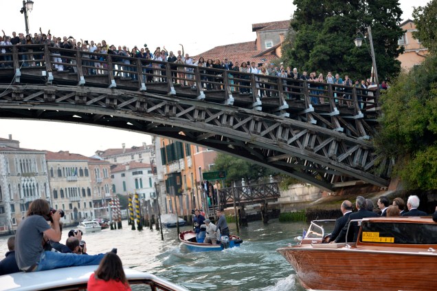 Dezenas de pessoas e fotógrafos acenam de uma ponte para o barco onde o ator americano George Clooney segue para a cerimônia de casamento com a britânica Amal Alamuddin, em Veneza, na Itália