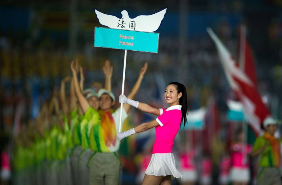 Voluntária é fotografada durante cerimônia de abertura dos Jogos Olímpicos da Juventude. Mais de 3.700 atletas com idades entre 15 e 18 anos participaram dos jogos, buscando uma vaga nos Jogos de 2016 no Rio de Janeiro