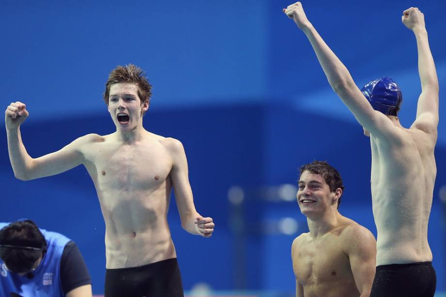 Atletas da Grã-Bretanha, Duncan Scott, Miles Munro e Martyn Walton, comemoram vitória no revezamento 100m livre da natação