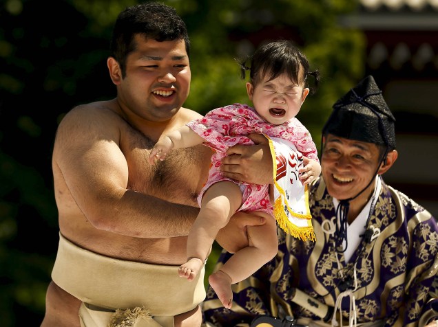 Lutador de sumô amador segura uma criança durante um concurso de choro de bebê em Tóquio, no Japão