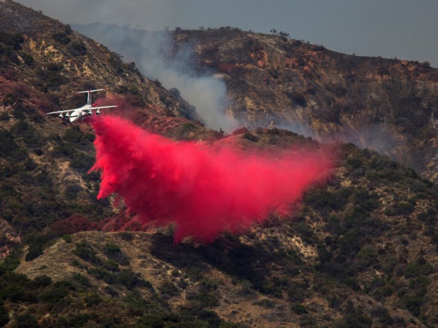 Avião despeja subsância retardadora de fogo na região da Monrovia, na Califórnia
