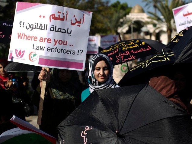 Mulher palestina mostra cartaz escrito Onde estão vocês, forças da lei? durante protesto, na cidade de Gaza, pelo dia internacional dos Direitos Humanos